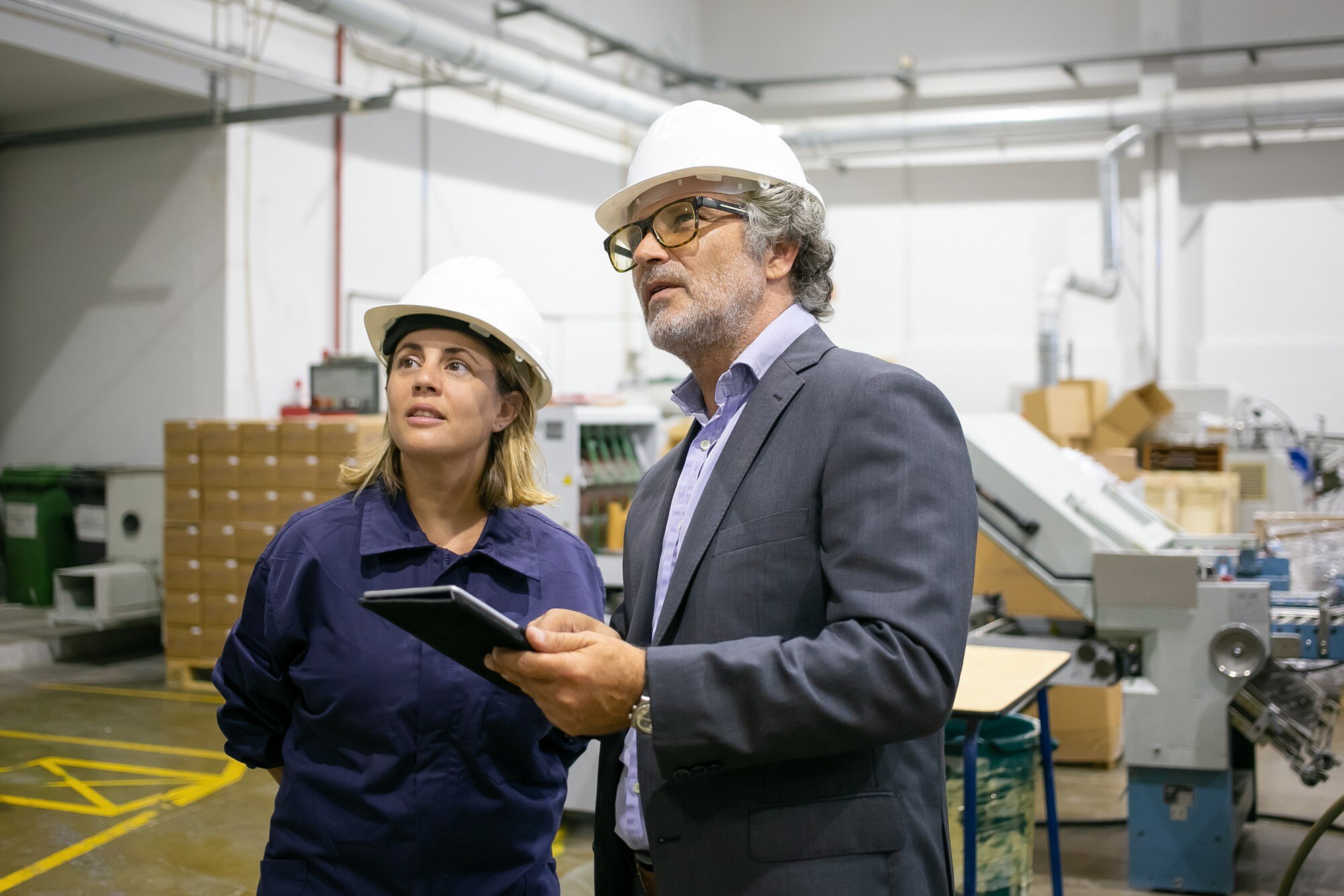 supervisore-barbuto-fiducioso-che-parla-con-l-operaio-femminile-della-pianta-e-che-tiene-compressa_74855-16353